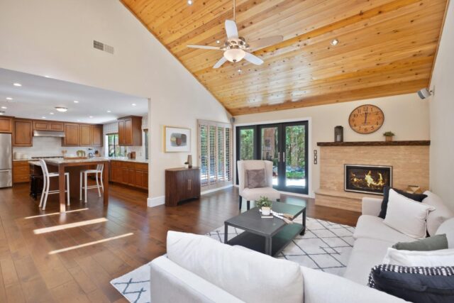 Inside of a home showing the living room and firepace and a kitchen 